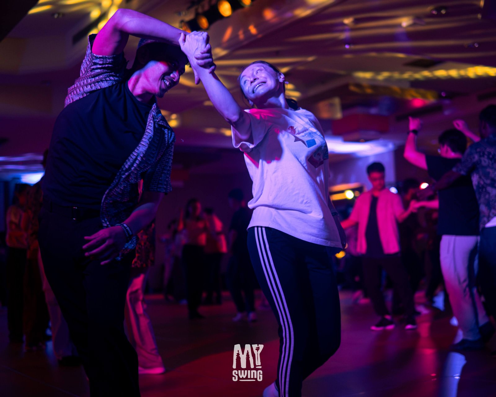 Smiling partners dance through an overhead turn at MY Swing 2025.