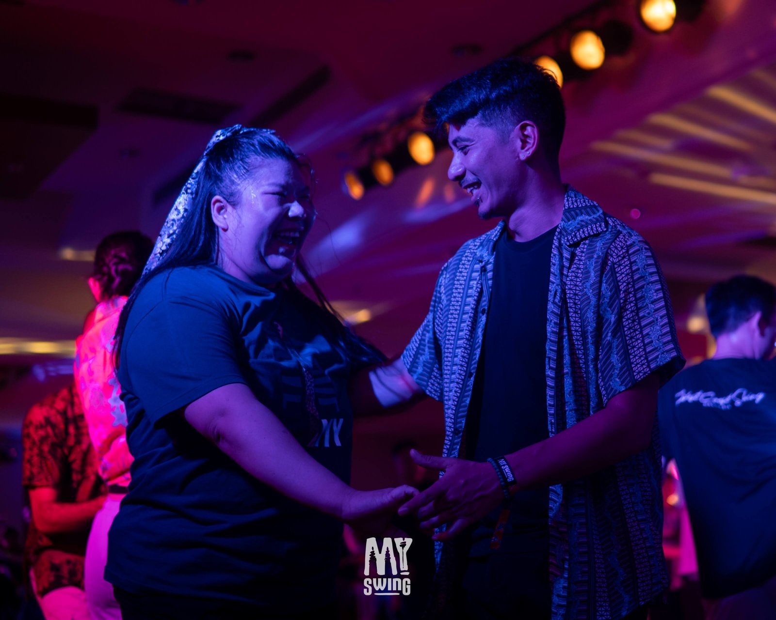 Two smiling partners dance beneath magenta lights at MY Swing 2025.