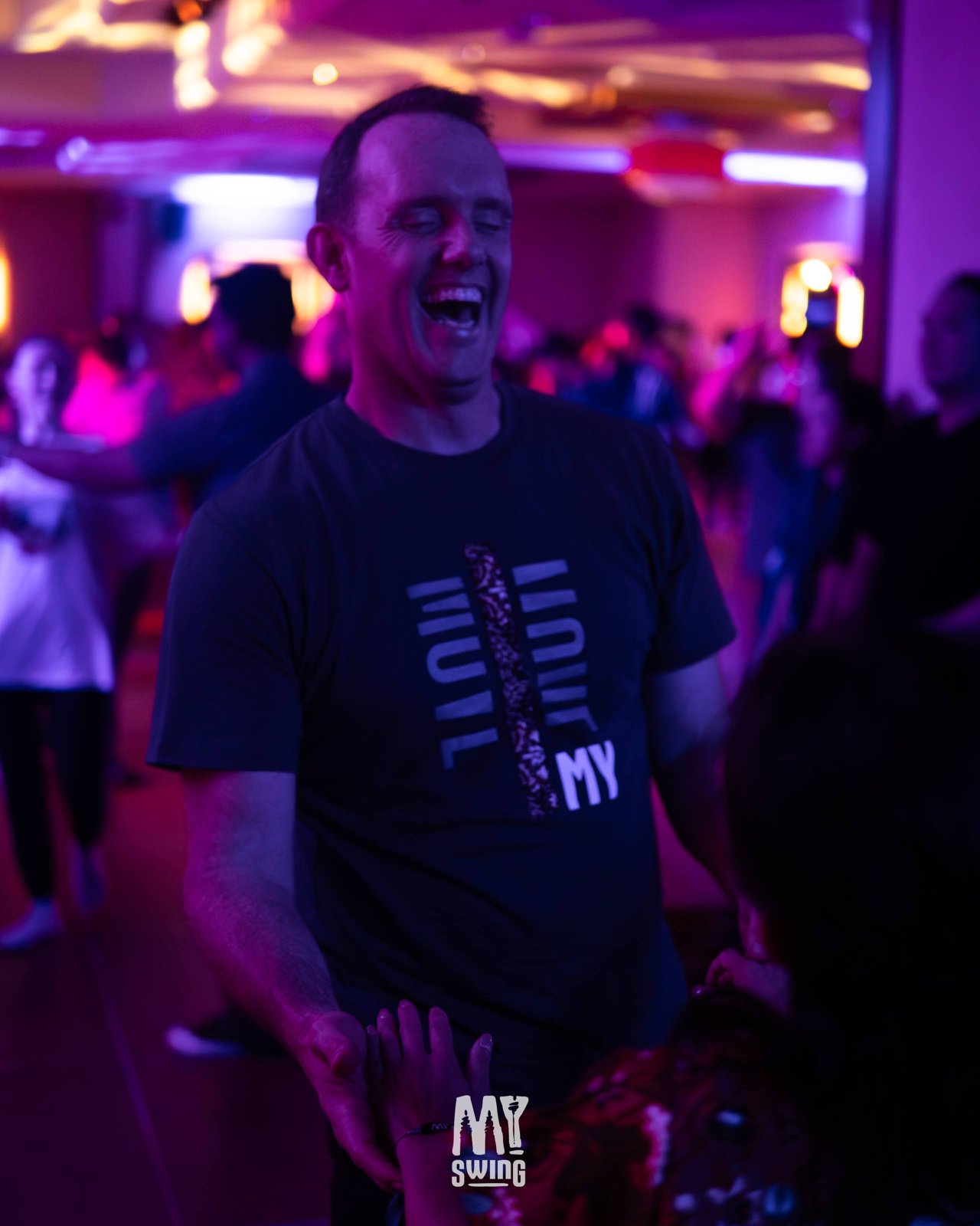 An attendee laughs among dancers on the social floor at MY Swing 2025.