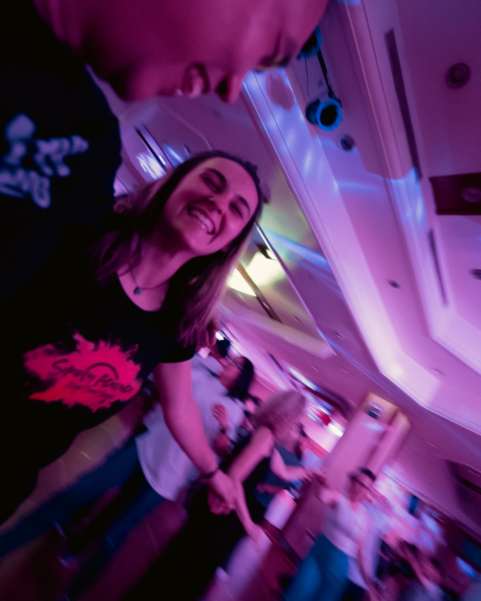 A smiling dancer looks toward the camera under violet event lights.