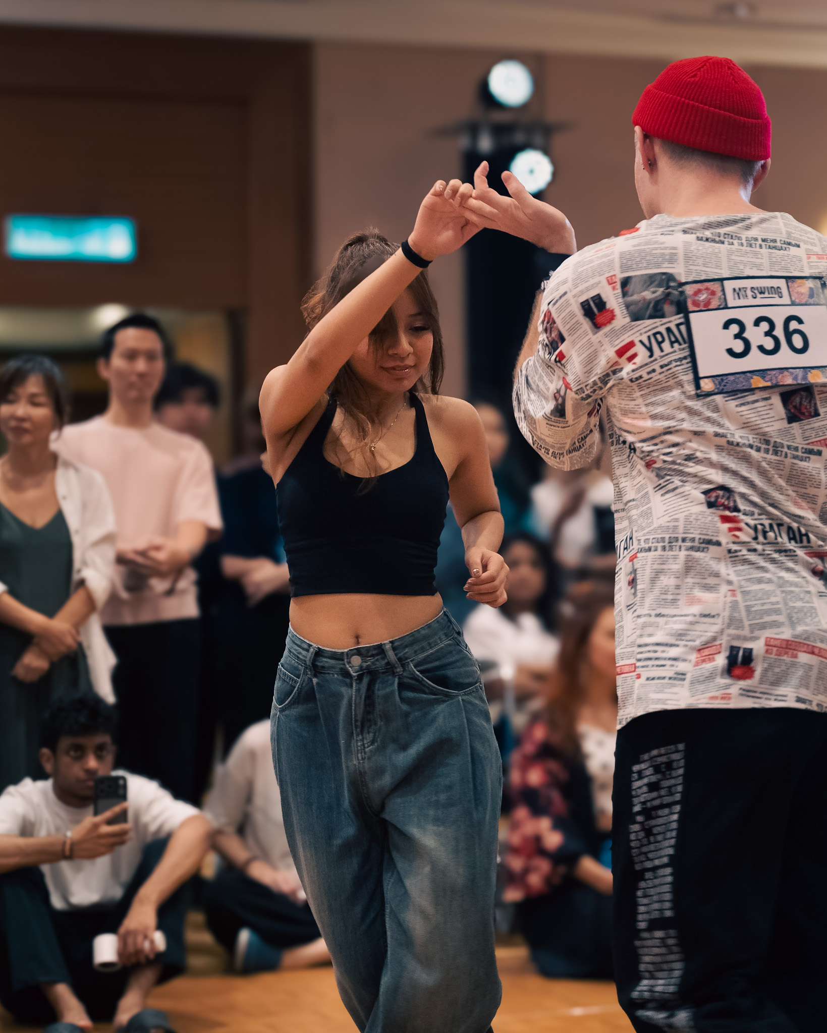 A competition couple connects hands as the crowd watches.
