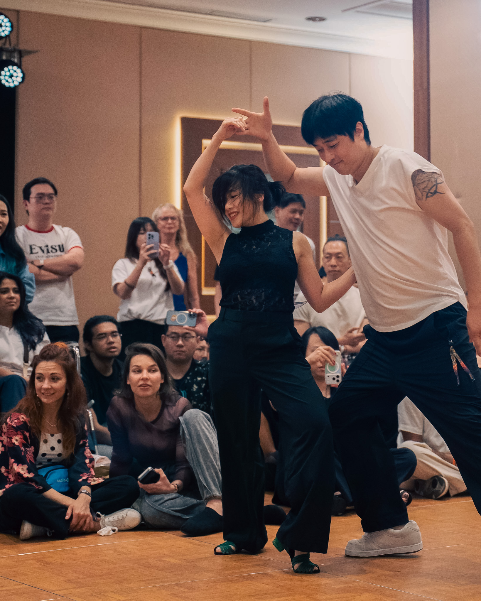 A pair dances energetically as spectators watch.