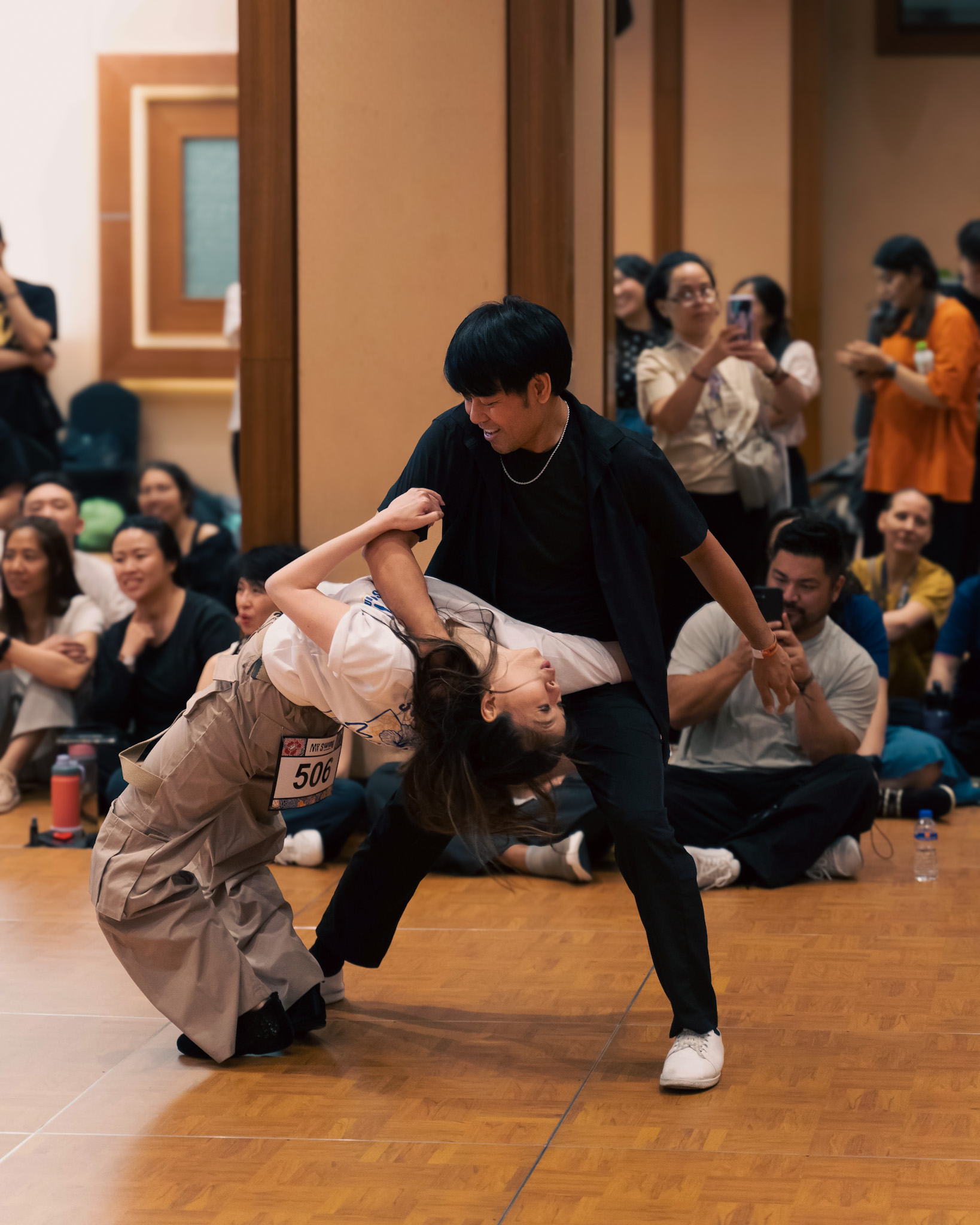 A dancer dips deeply as their partner supports the move.