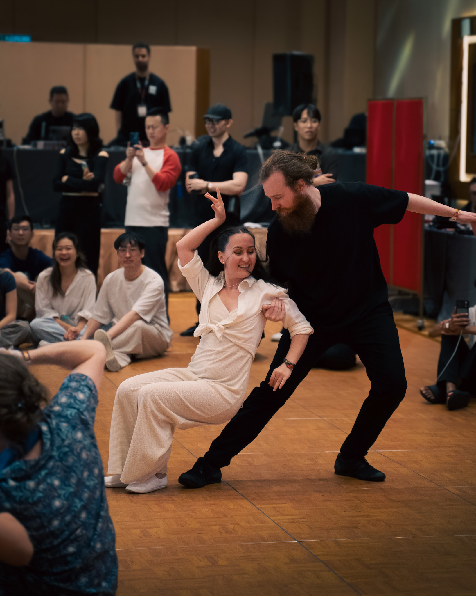 A pair performs a theatrical low pose before the audience.