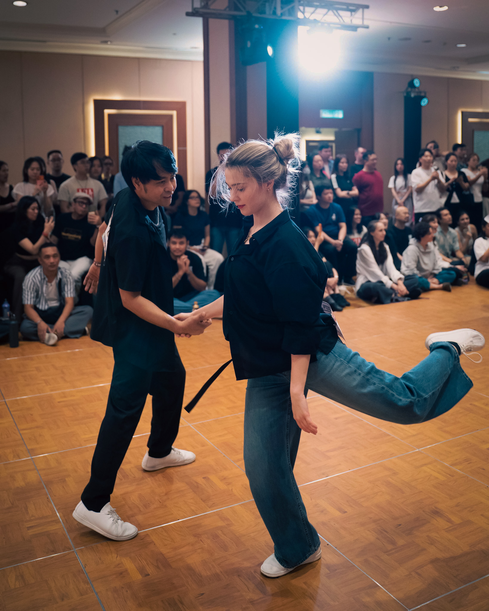 A dancer lifts one leg in a playful competition moment.