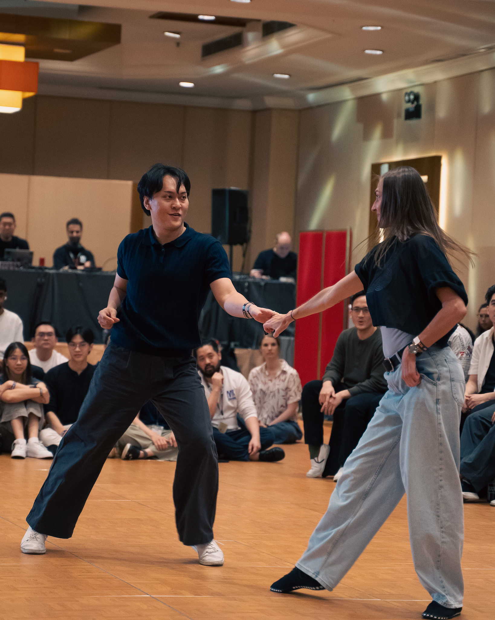 A pair stretches apart while keeping their hands connected.