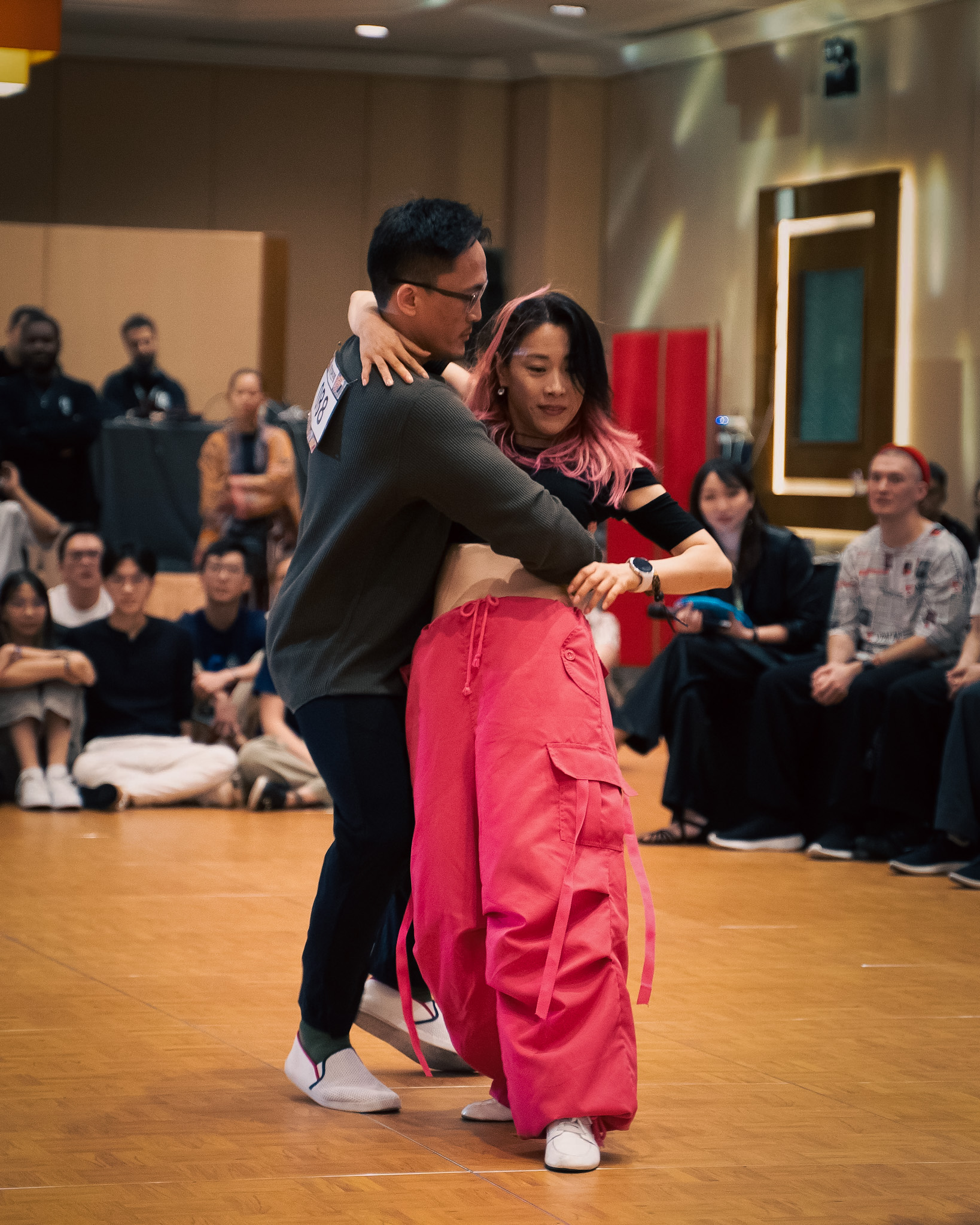 A couple dances closely in front of a cheering audience.