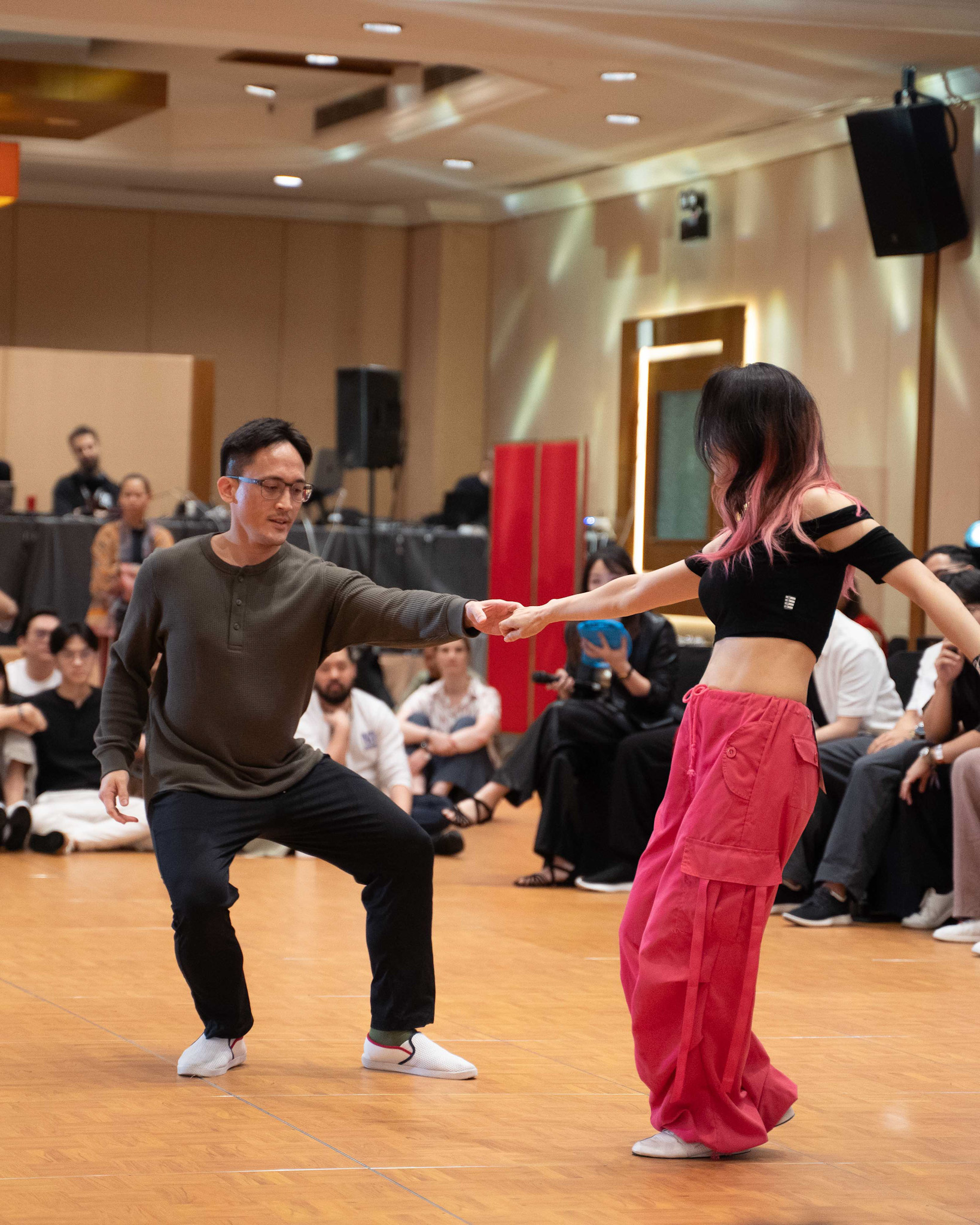 A dancer drops low while their partner extends an arm.