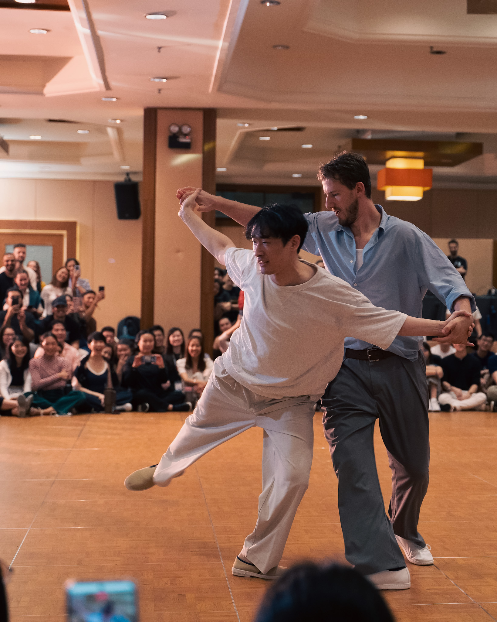 A couple extends into an open position before the seated crowd.