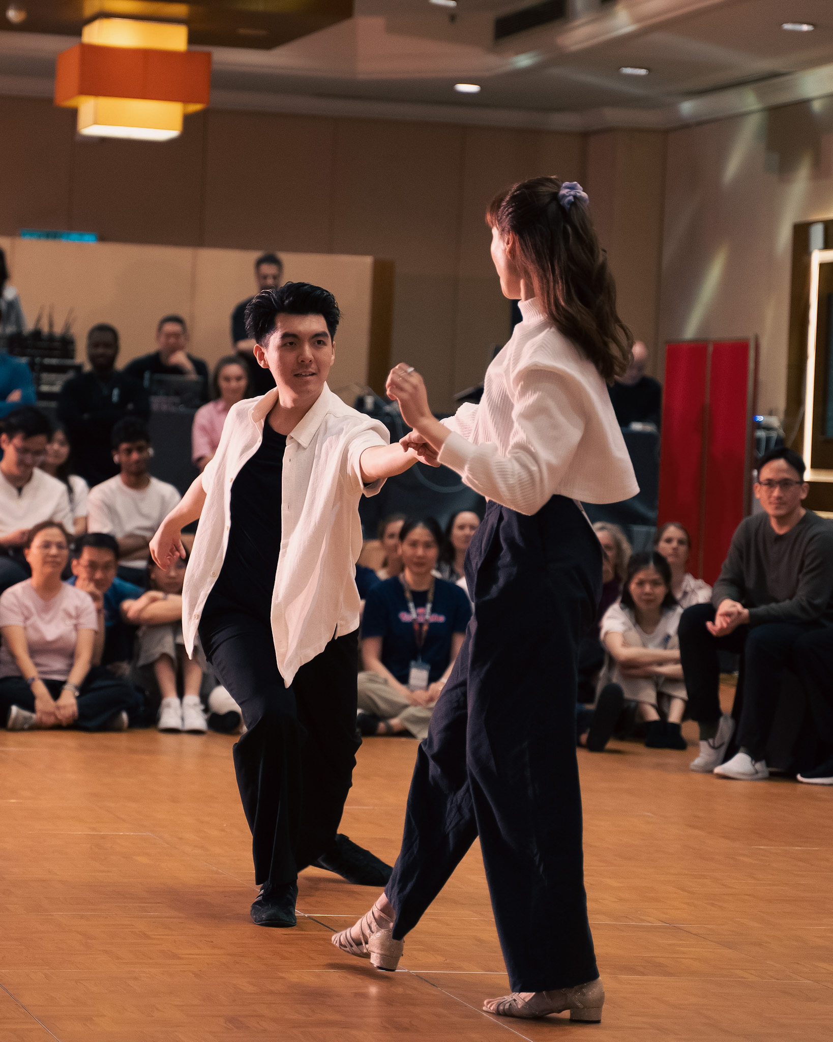 A pair dances together as spectators watch from the ballroom.