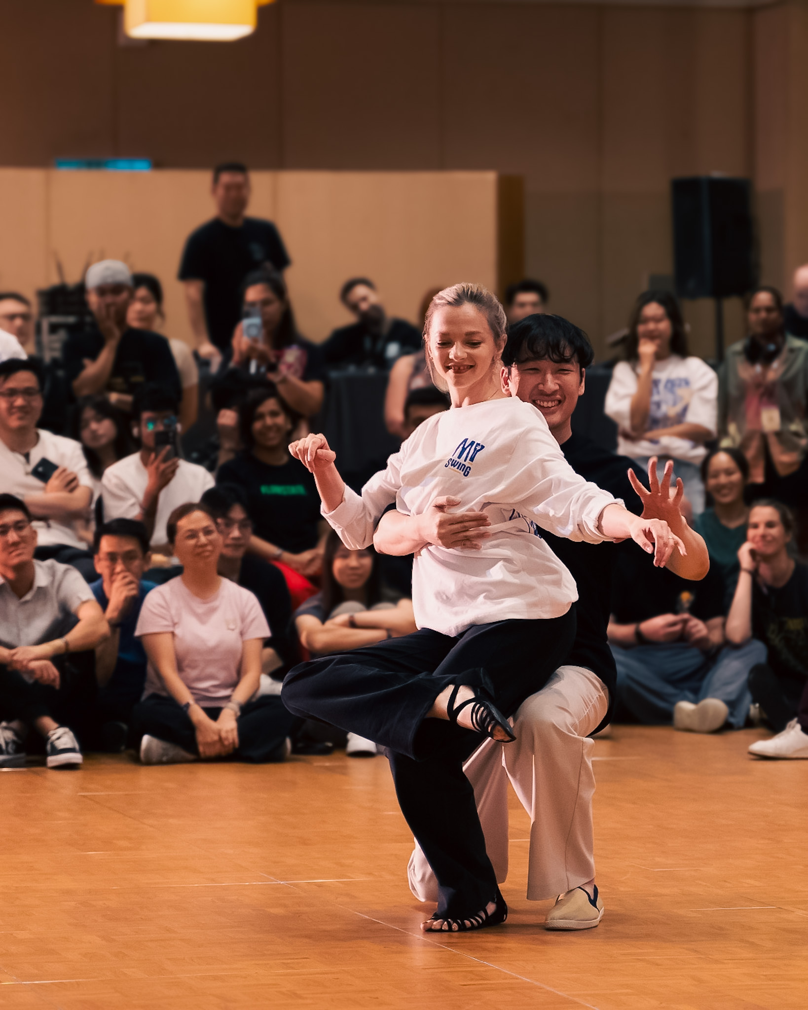 A smiling competitor strikes a playful pose near their partner.