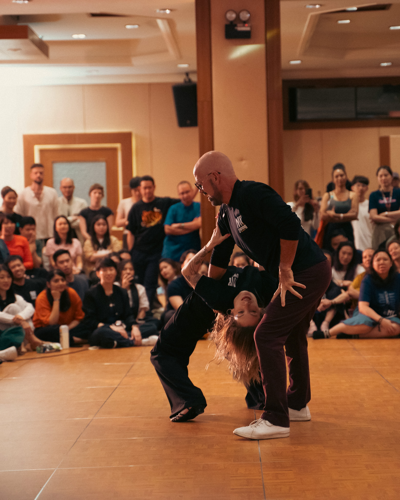 Performers balance in a supported pose before the audience.