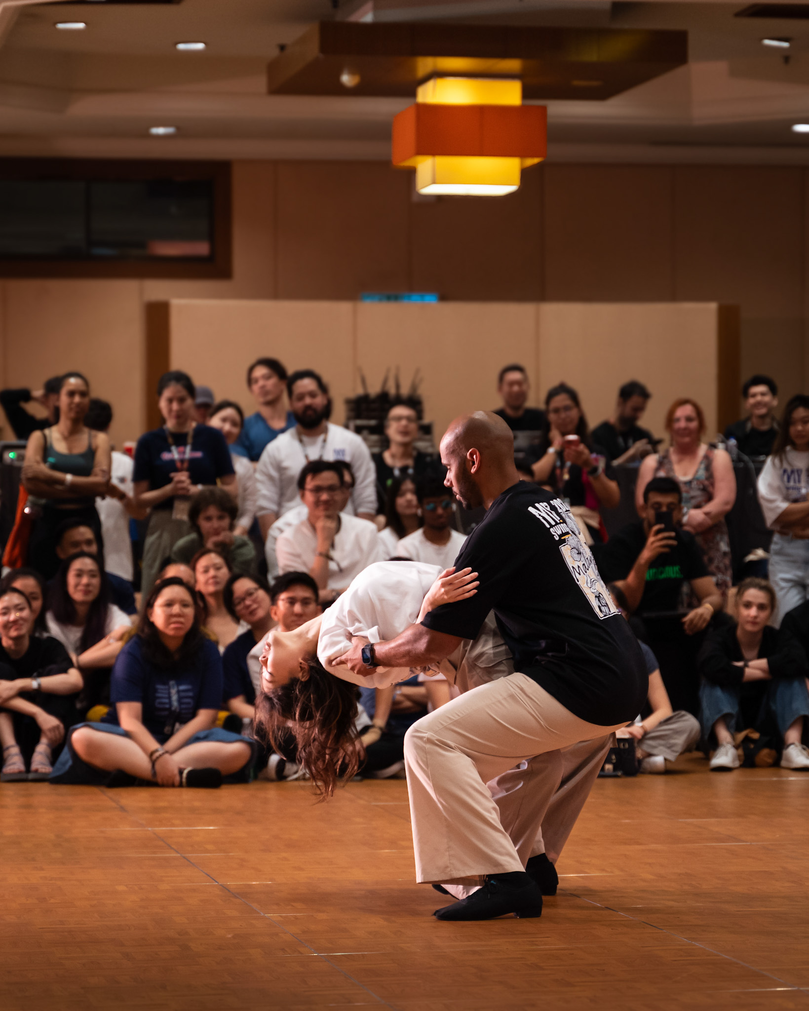 One performer supports their partner in a low seated pose.