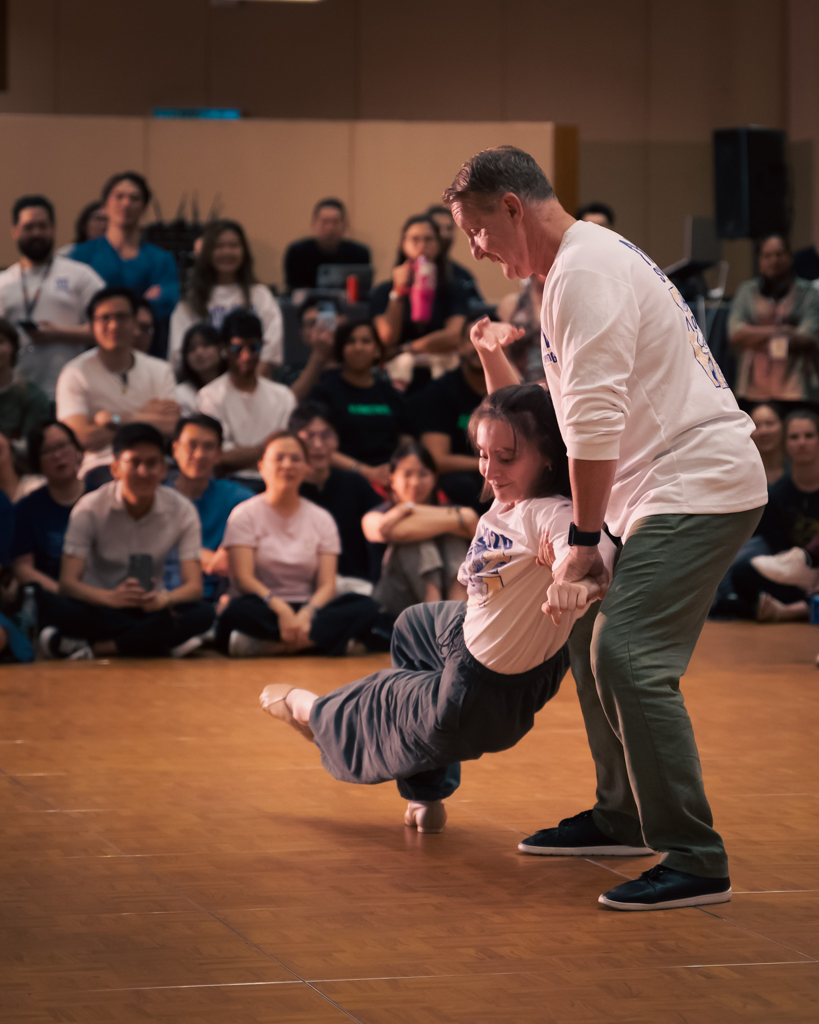 A dancer balances in a supported low pose.