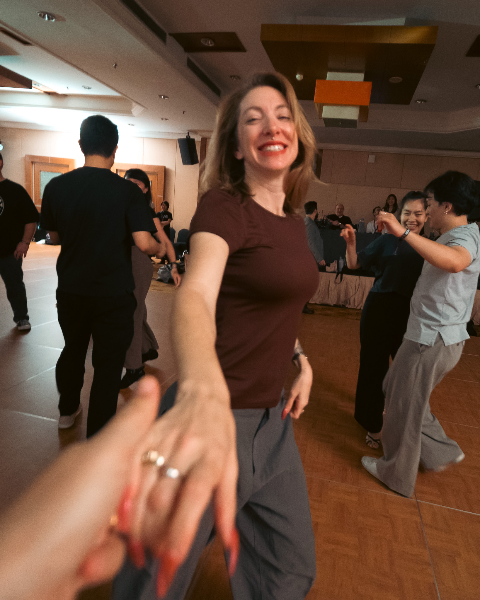 A smiling dancer reaches toward the camera while people dance and gather in the hall at MY Swing 2026.