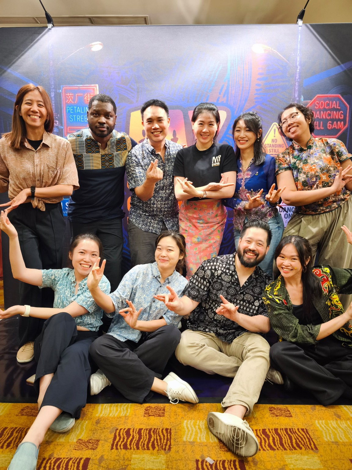 A group in colourful patterned clothes poses together at the MY Swing 2026 backdrop.