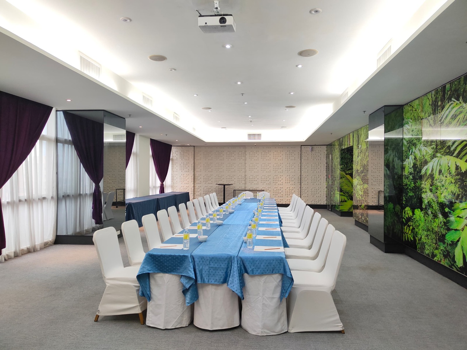 A bright meeting room at Vivatel Kuala Lumpur with windows and botanical wall artwork